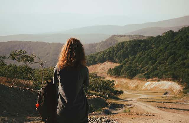 A woman with a backpack hitchhiking.
