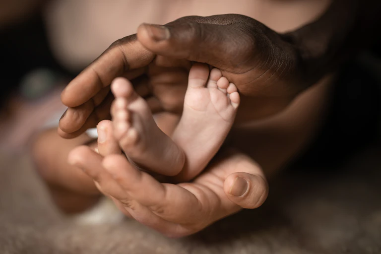 Adult hands hold baby's feet