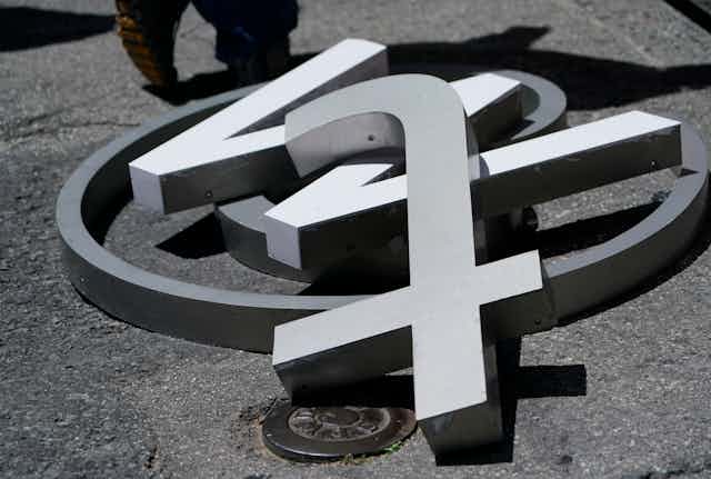 A large @ symbol, w and t lying on a street in close up.