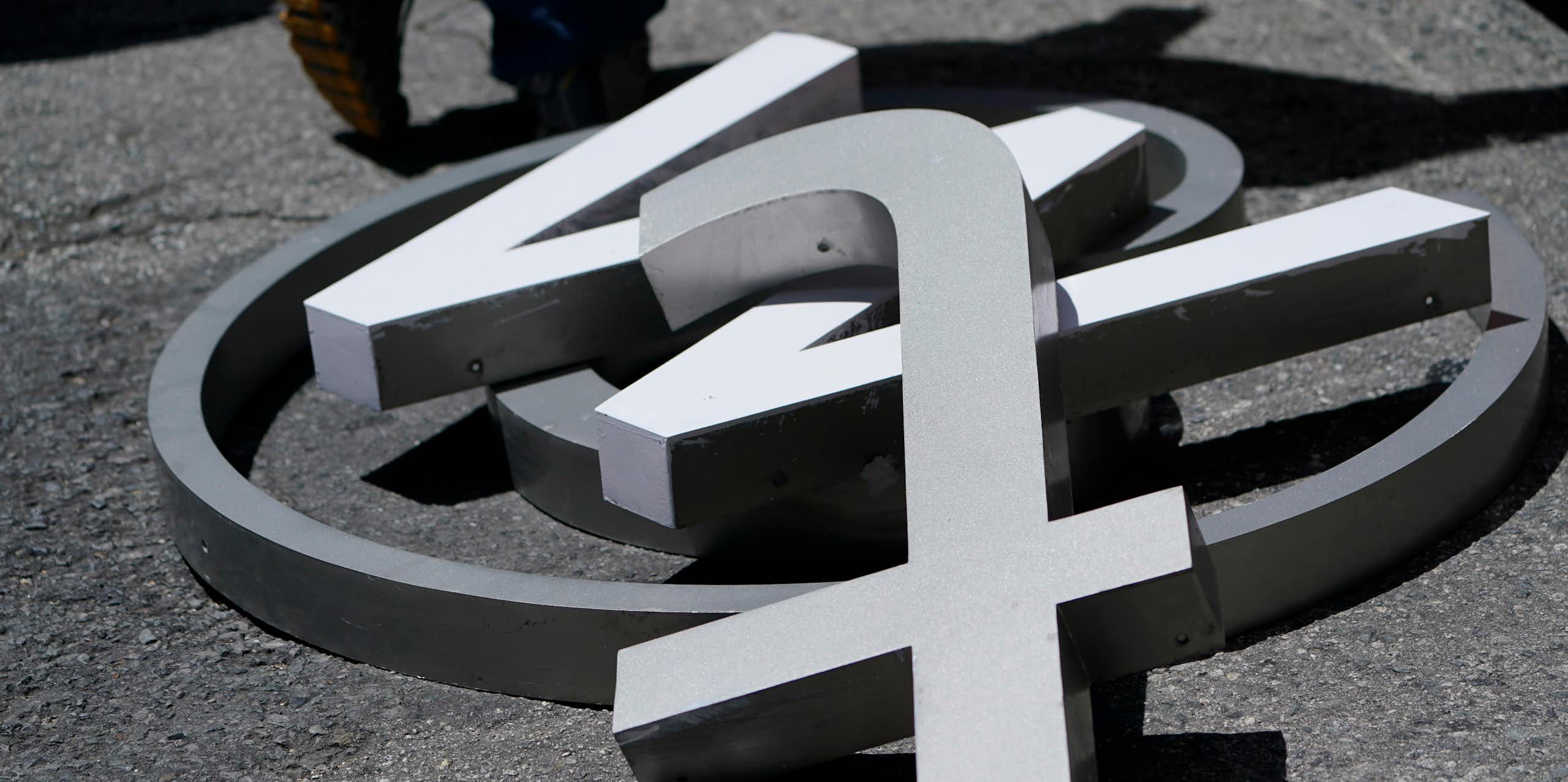 A large @ symbol, w and t lying on a street in close up.