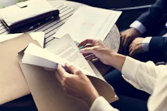 Unidentified man goes through a folder while another man sits nearby