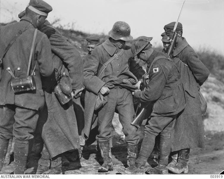 Australian soldiers search their German prisoners.