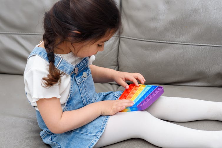 girl sits on couch with colourful fidget toy