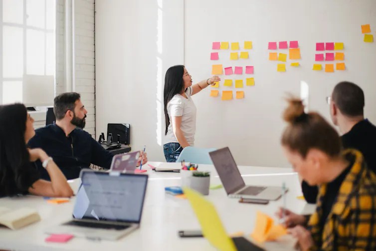 open meeting room with people putting ideas on colourful notes on wall