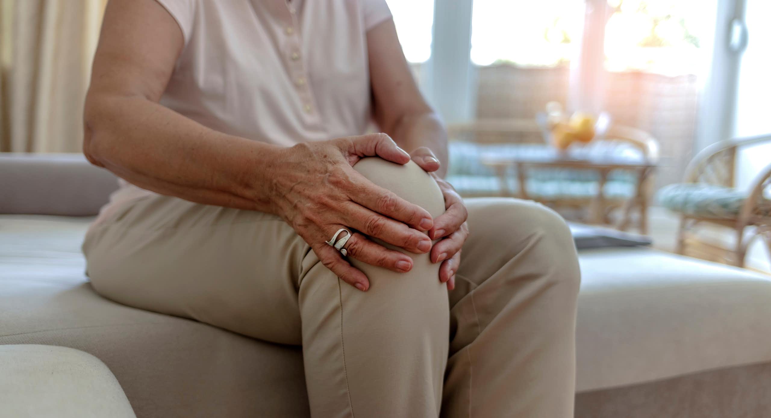 Photo d’une femme âgée se tenant le genou, visiblement douloureux.