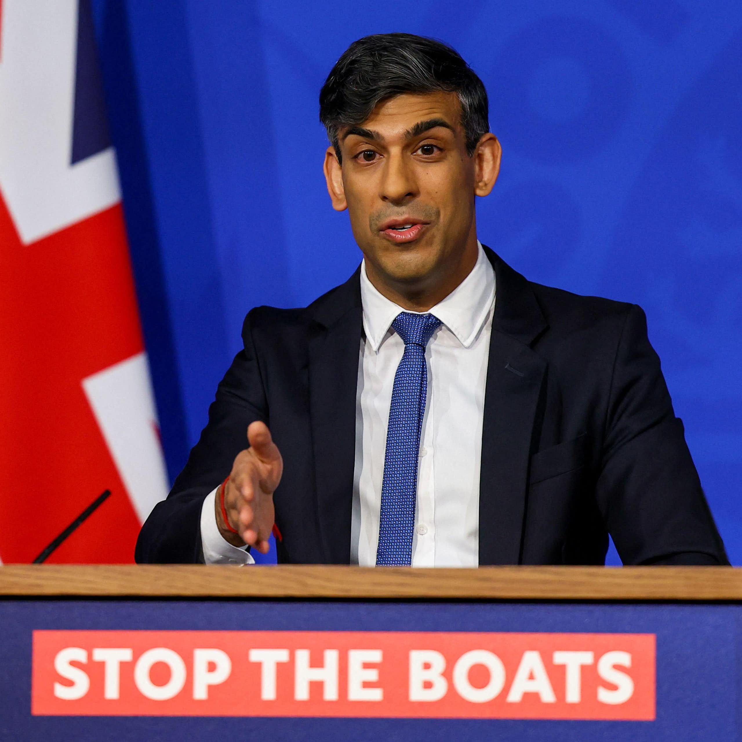 Rishi Sunak speaking and gesturing decisively at a podium that reads Stop the Boats