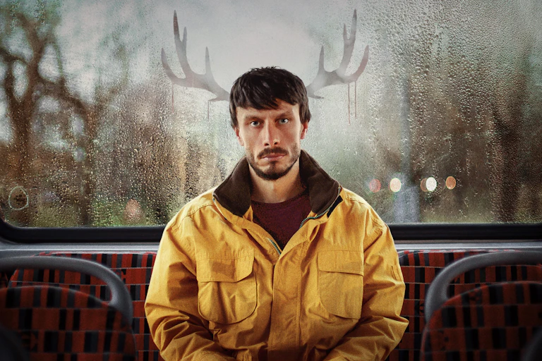 Donny on the bus with reindeer antlers drawn into the condensation in window behind him
