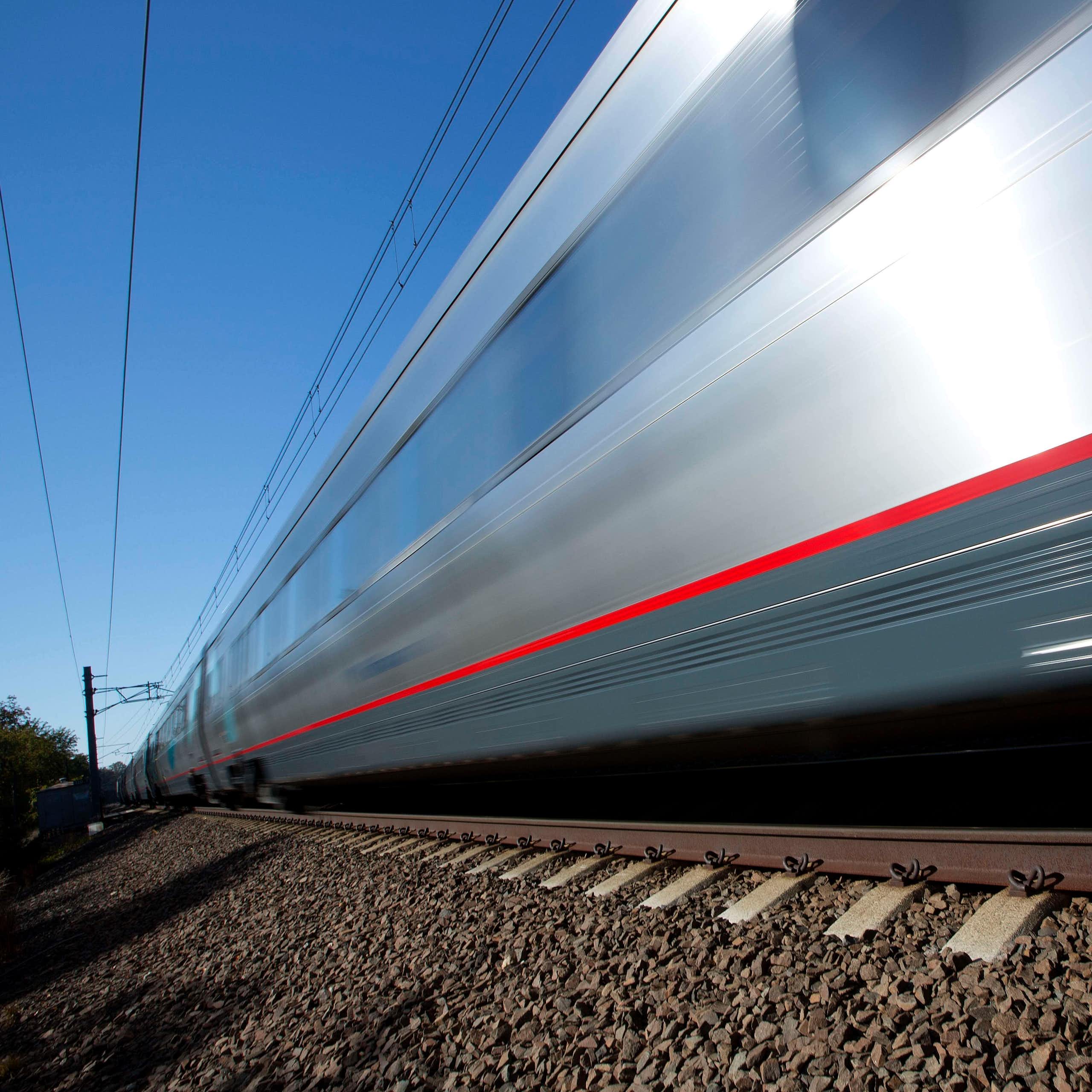 A silver train speeds through the frame, slightly blurred