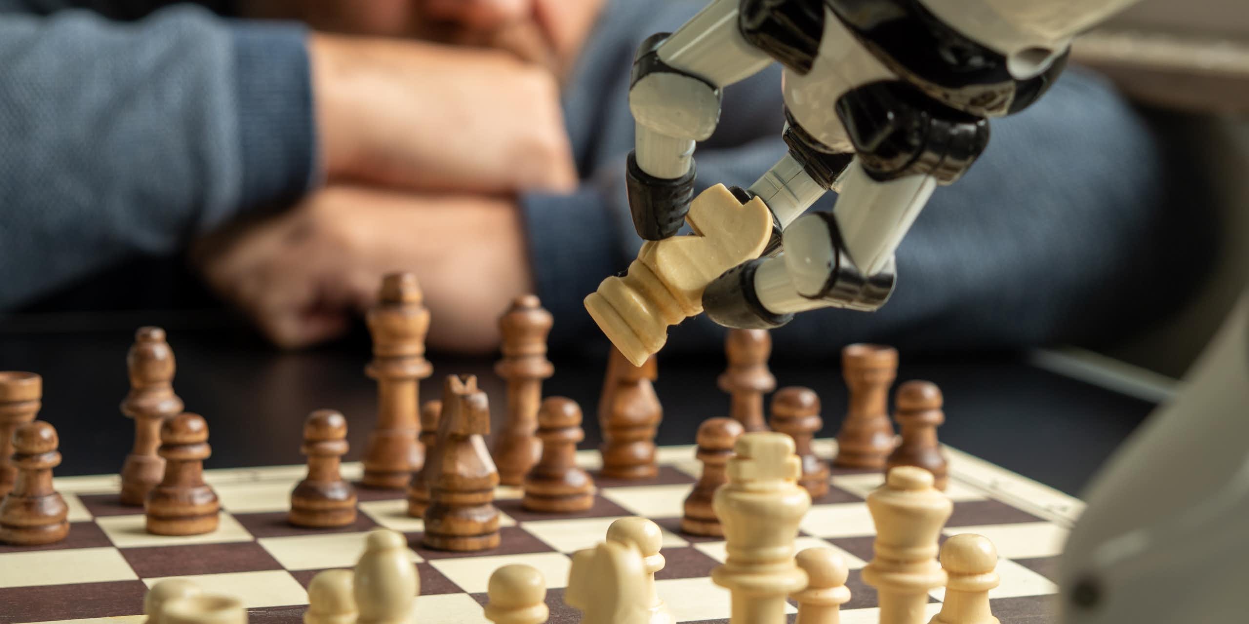 Um braço robótico agarra uma peça de xadrez em um jogo contra um humano