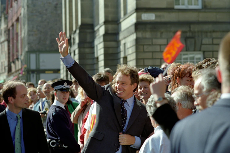 Tony Blair waving in a crowd of supporters.