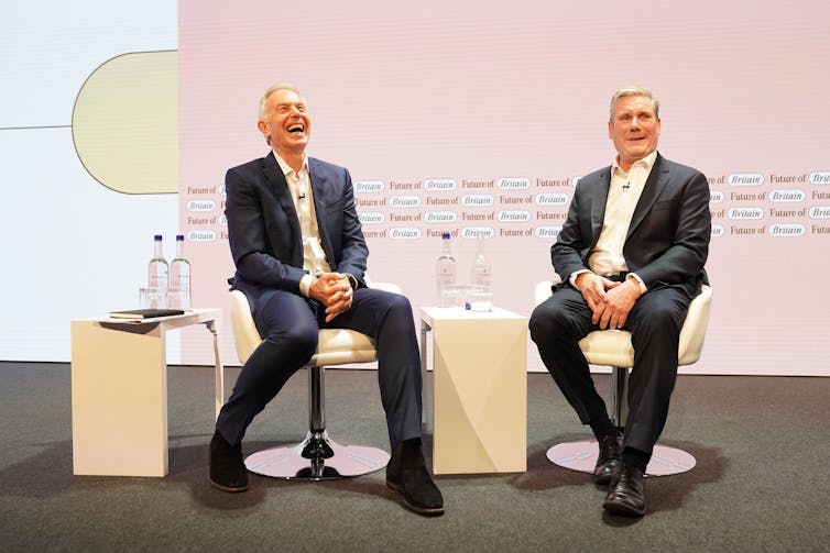 Tony Blair and Keir Starmer siting on a stage.