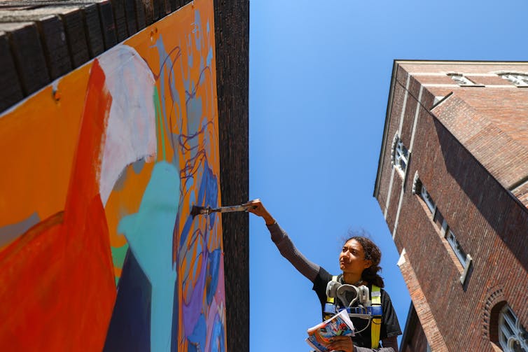 A person seen with a brush painting a mural.