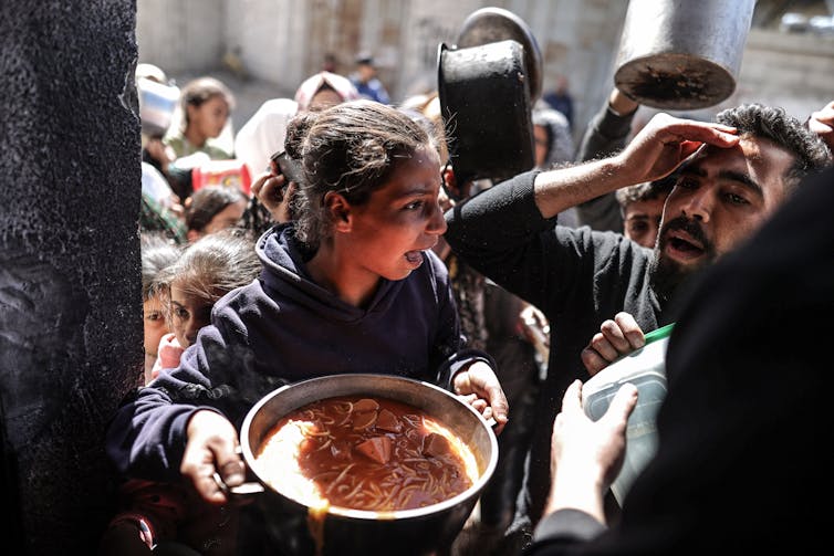 A girl carries pot of food.