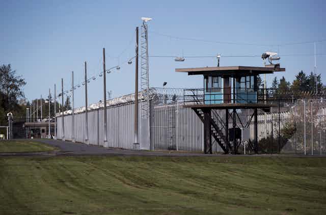 A guard tower next to a tall metal fence with barbed wire