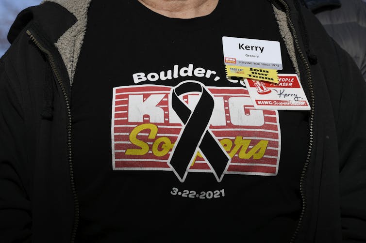 A woman wears a black shirt that features a black ribbon over the King Sooper grocery logo.