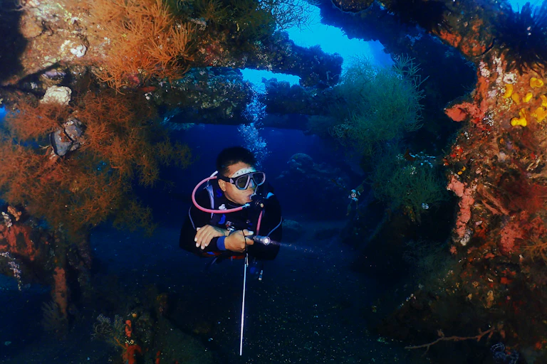 A person dives near a shipwreck in Bali.