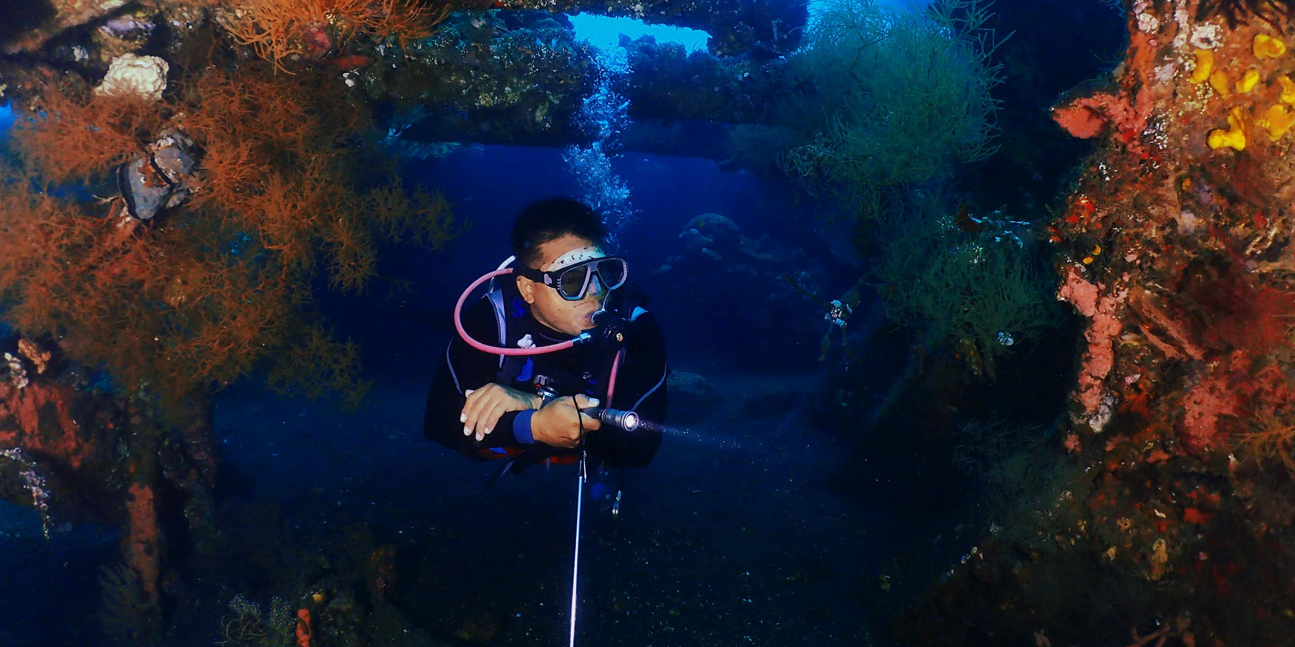 A person dives near a shipwreck in Bali.