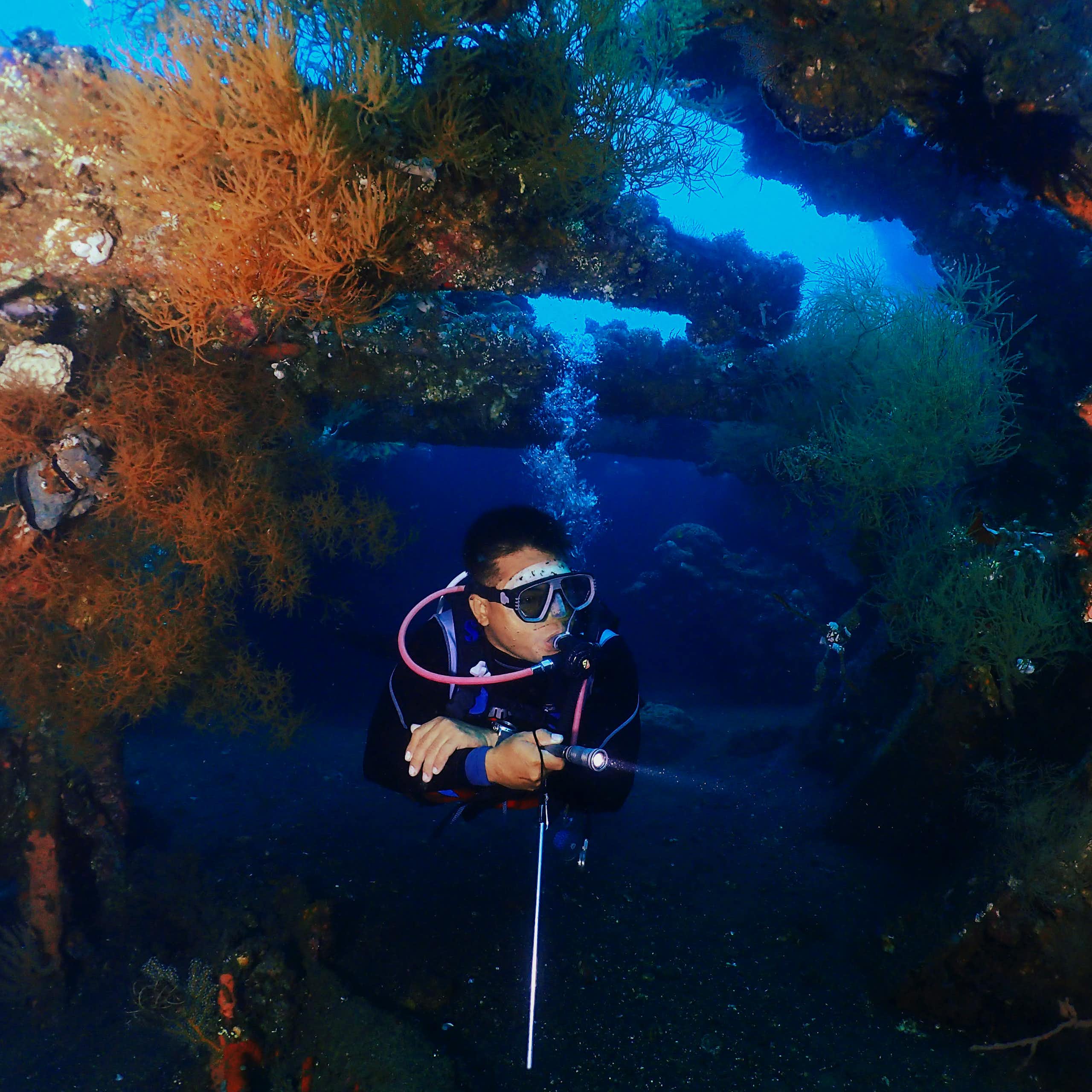 A person dives near a shipwreck in Bali.