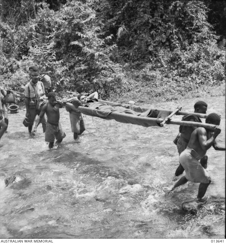 Wounded Australians being carried by New Guinean stretcher bearers.