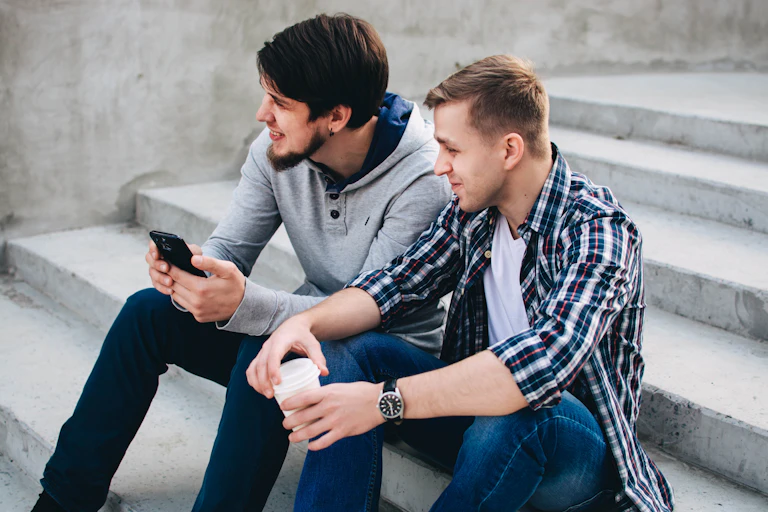 Two young men sit and chat on concrete steps