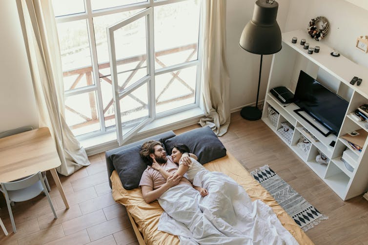 A birds-eye view of a couple lying in bed.