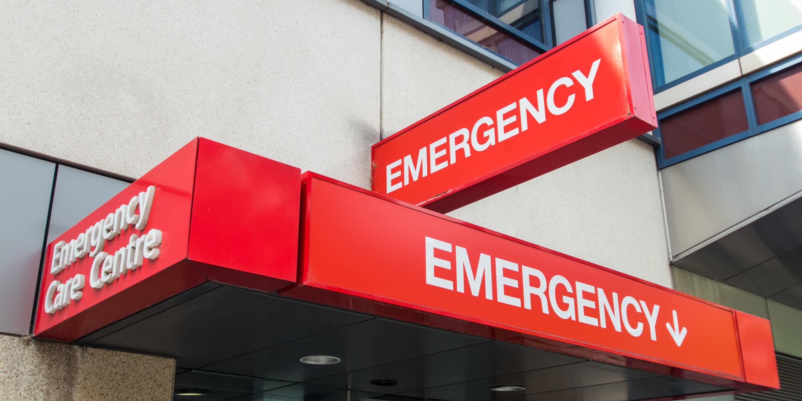 Red signs with white lettering reading 'emergency' outside building entrance