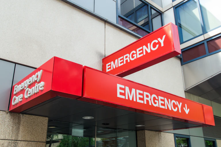 Red signs with white lettering reading 'emergency' outside building entrance