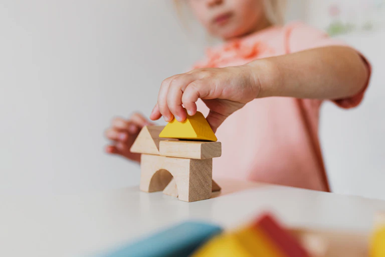 small girl plays with blocks on table