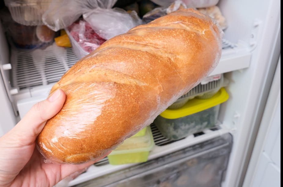 A person puts a loaf of bread in their freezer.