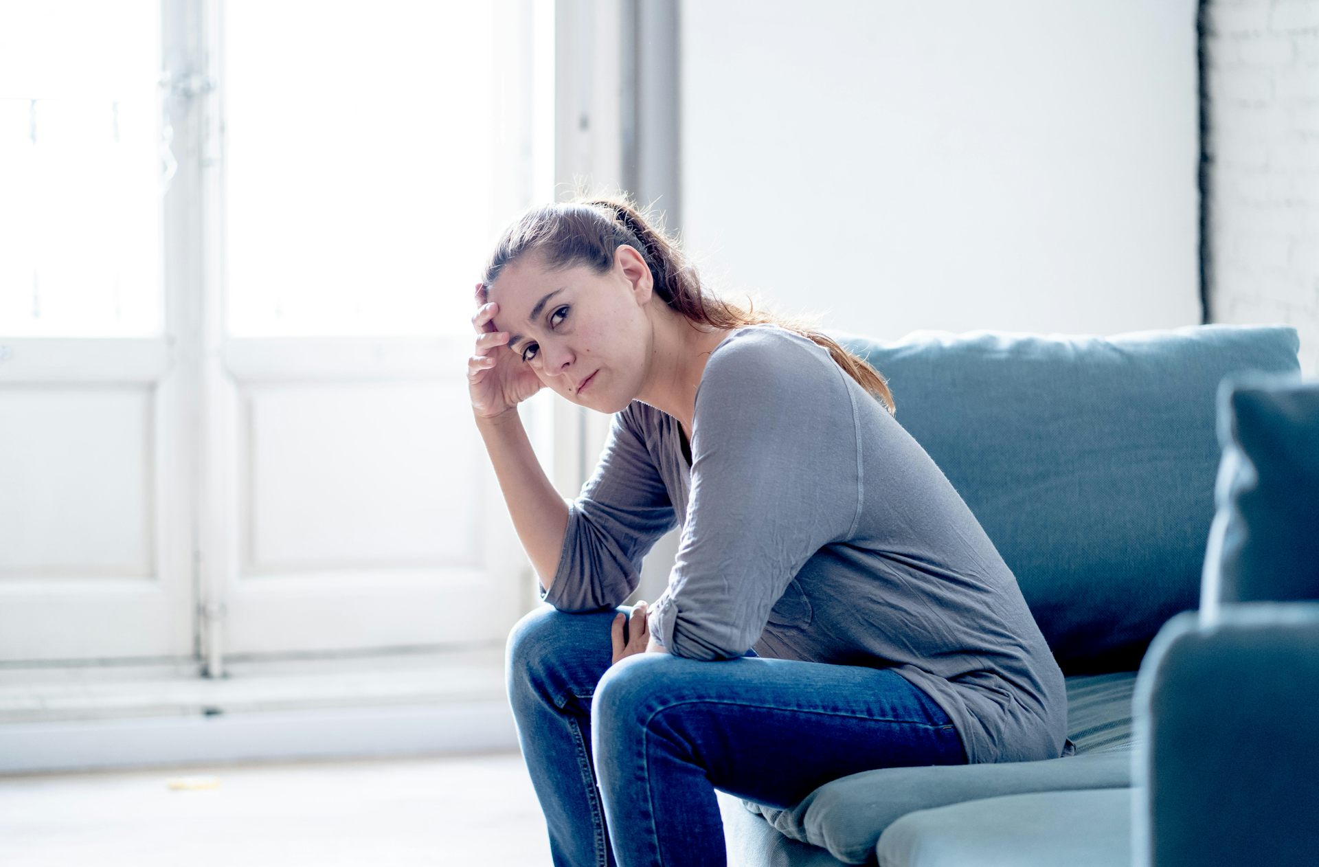 A woman in jeans sits on a couch.
