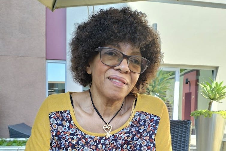 A woman with a short Afro and glasses smiles as she talks.