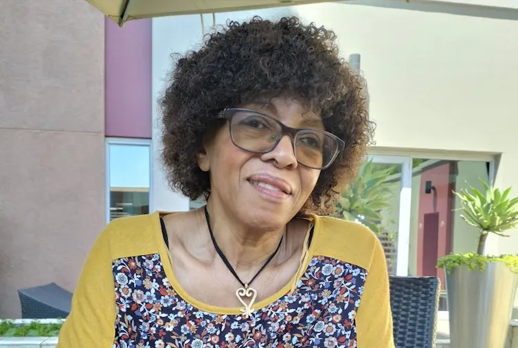 A woman with a short Afro and glasses smiles as she talks.