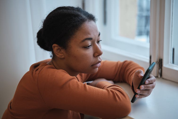 Sad woman reading her smart phone.