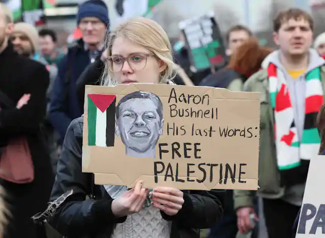 A protestor holding a placard reading "Aaron Bushnell, His last words: Free Palestine"