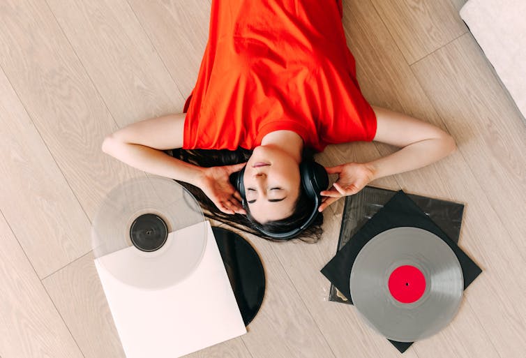 young woman lying down listening to vinyl