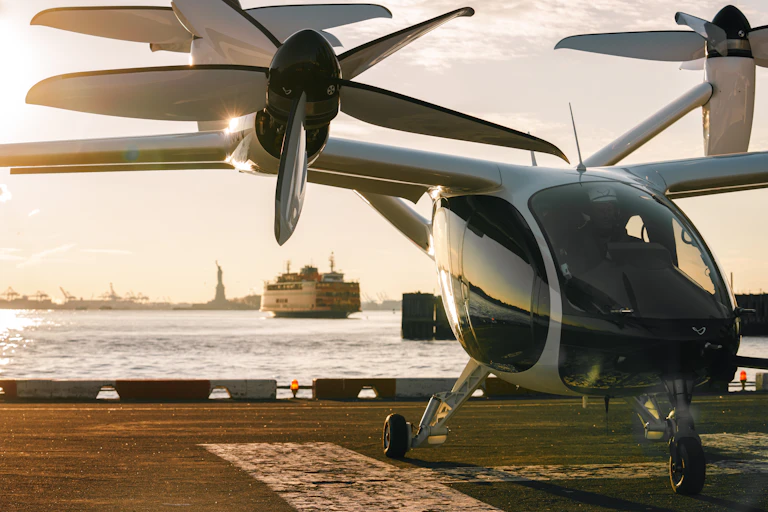 An eVTOL on a helipad in New York City with the Statue of Liberty in the background.