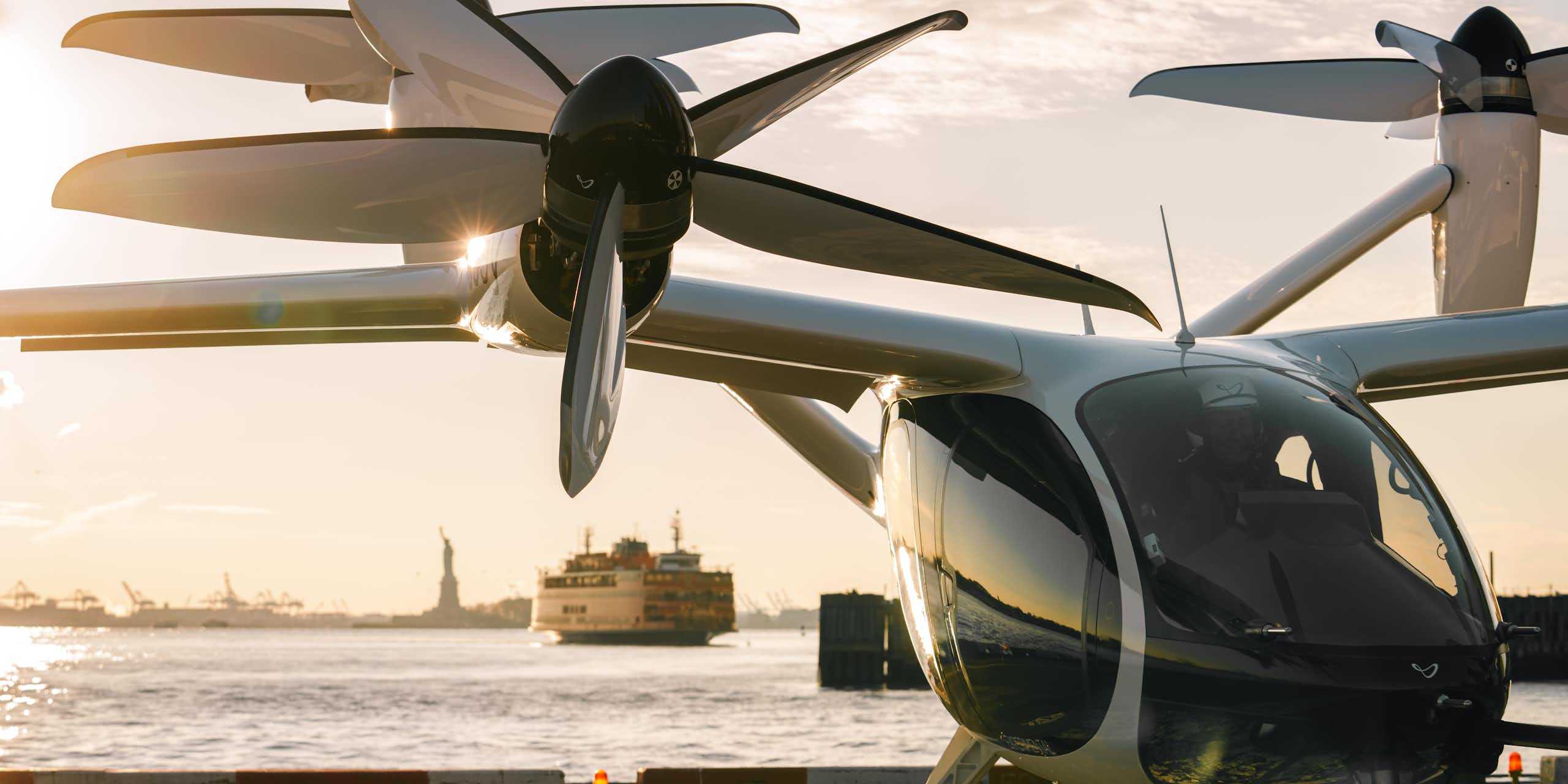 An eVTOL on a helipad in New York City with the Statue of Liberty in the background.