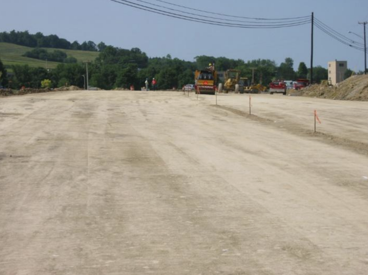 A sandy, grain-like material packed on the ground where a road will go.