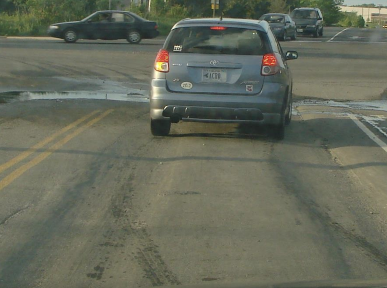 A car driving over a deep indent in the road.