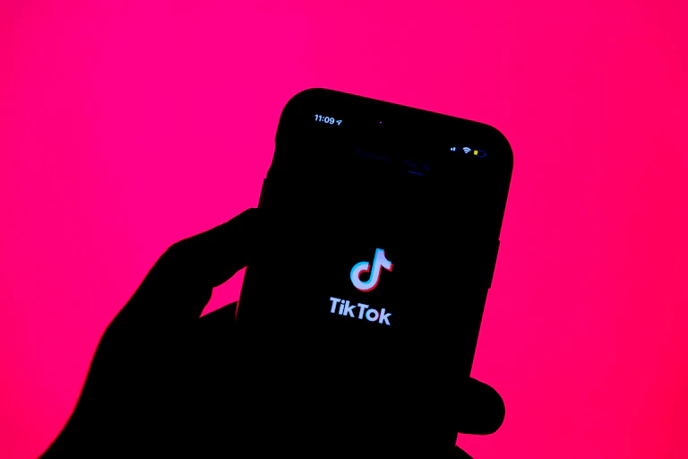 silhouette of a hand holding a smartphone with an app splash screen visible on the phone