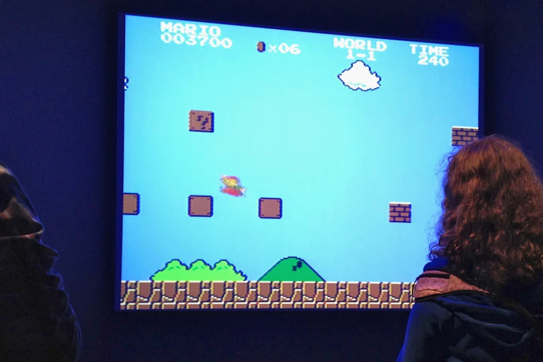 deux personnages jouent à un jeu vidéo sur un écran