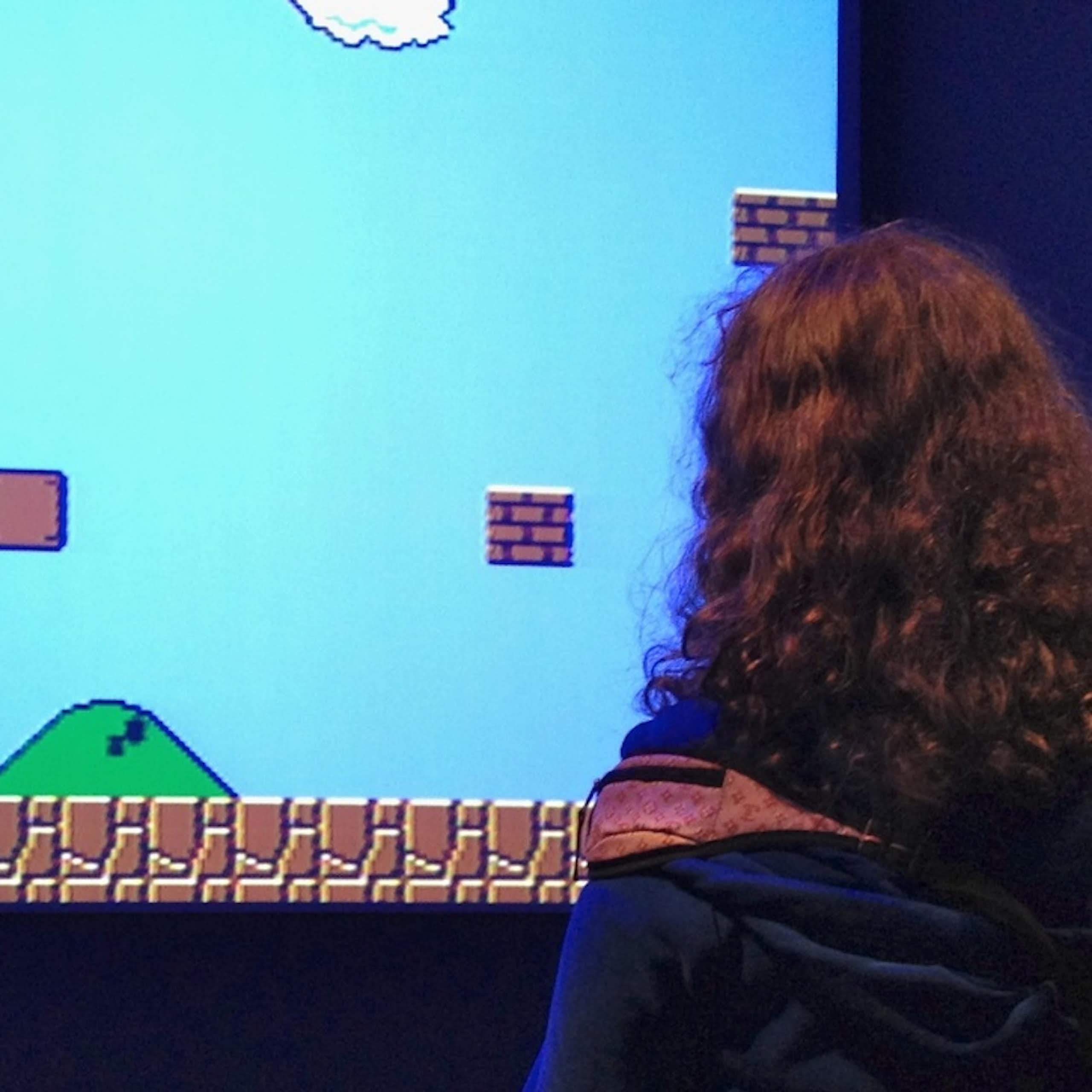 deux personnages jouent à un jeu vidéo sur un écran