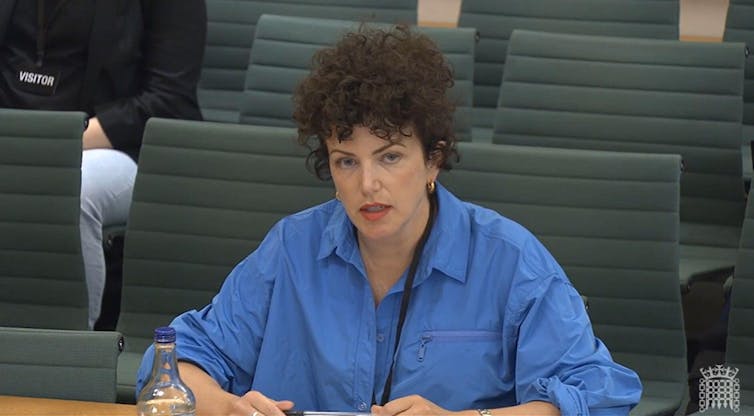 Annie Macmanus sat at a desk in a blue shirt.