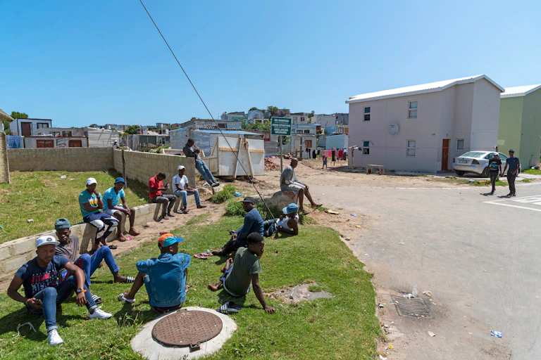 Young men sit on the side of the road.