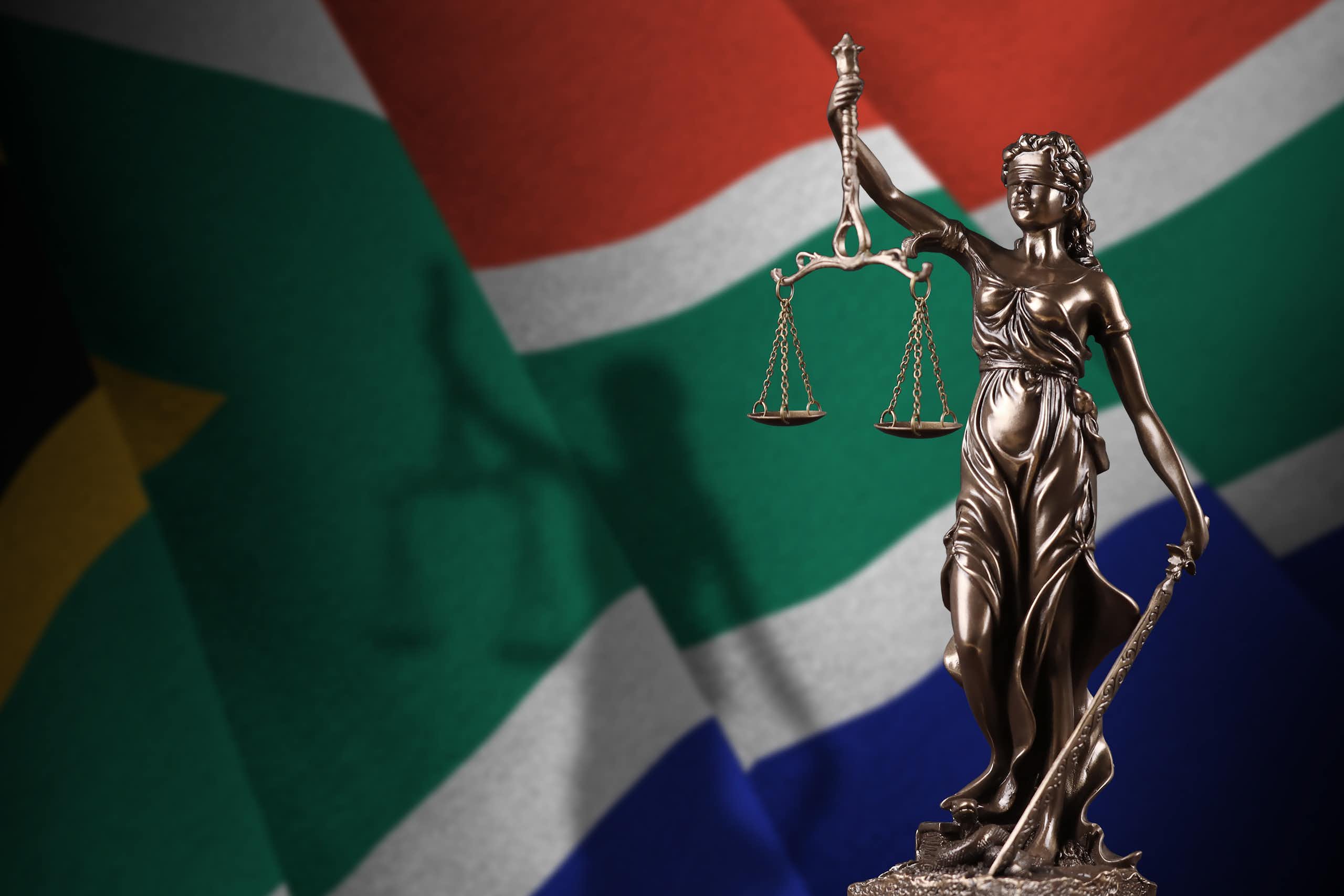 Lady Justice figurine superimposed over the South African flag.