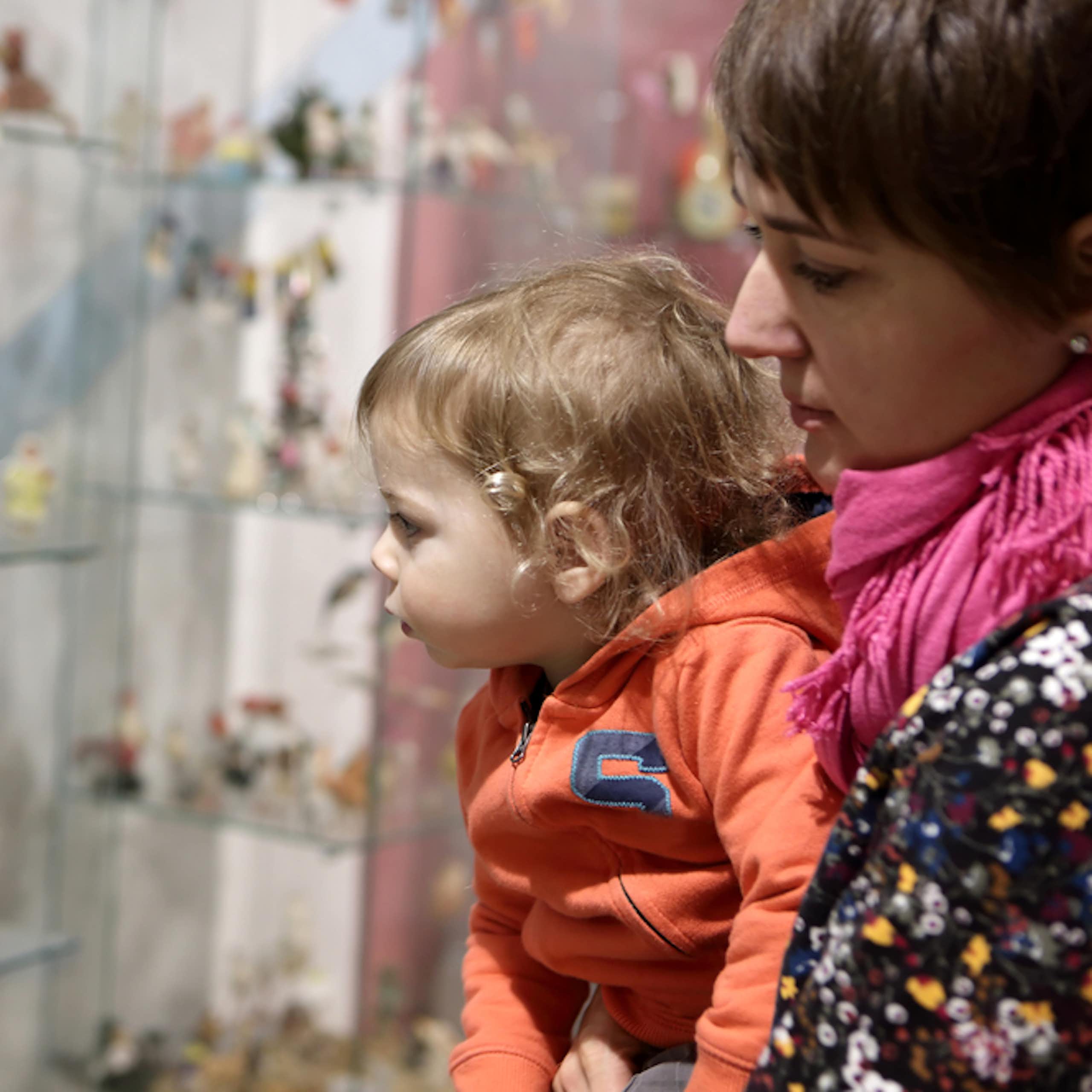 Un bébé dans les bras de sa mère regarde une vitrine au musée