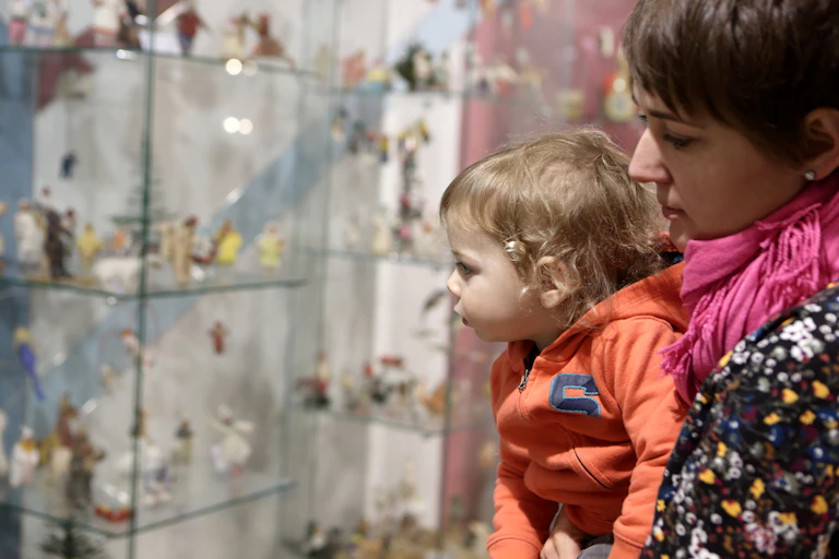 Un bébé dans les bras de sa mère regarde une vitrine au musée