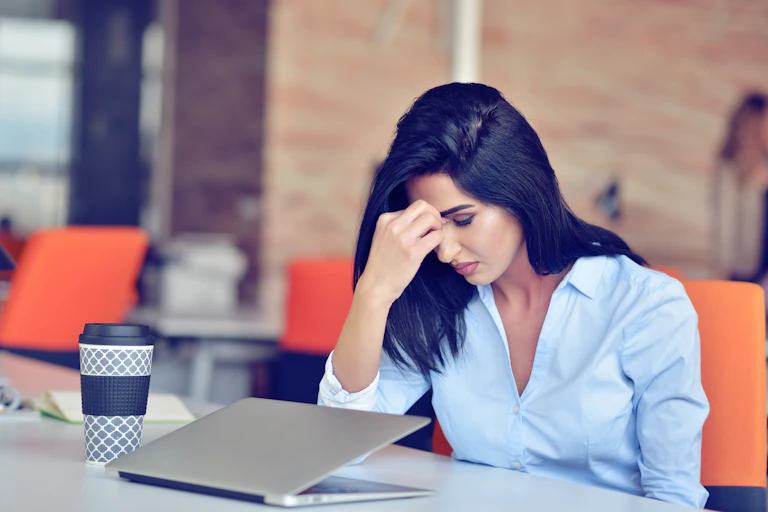 A young woman sits dejected in front of a closed laptop