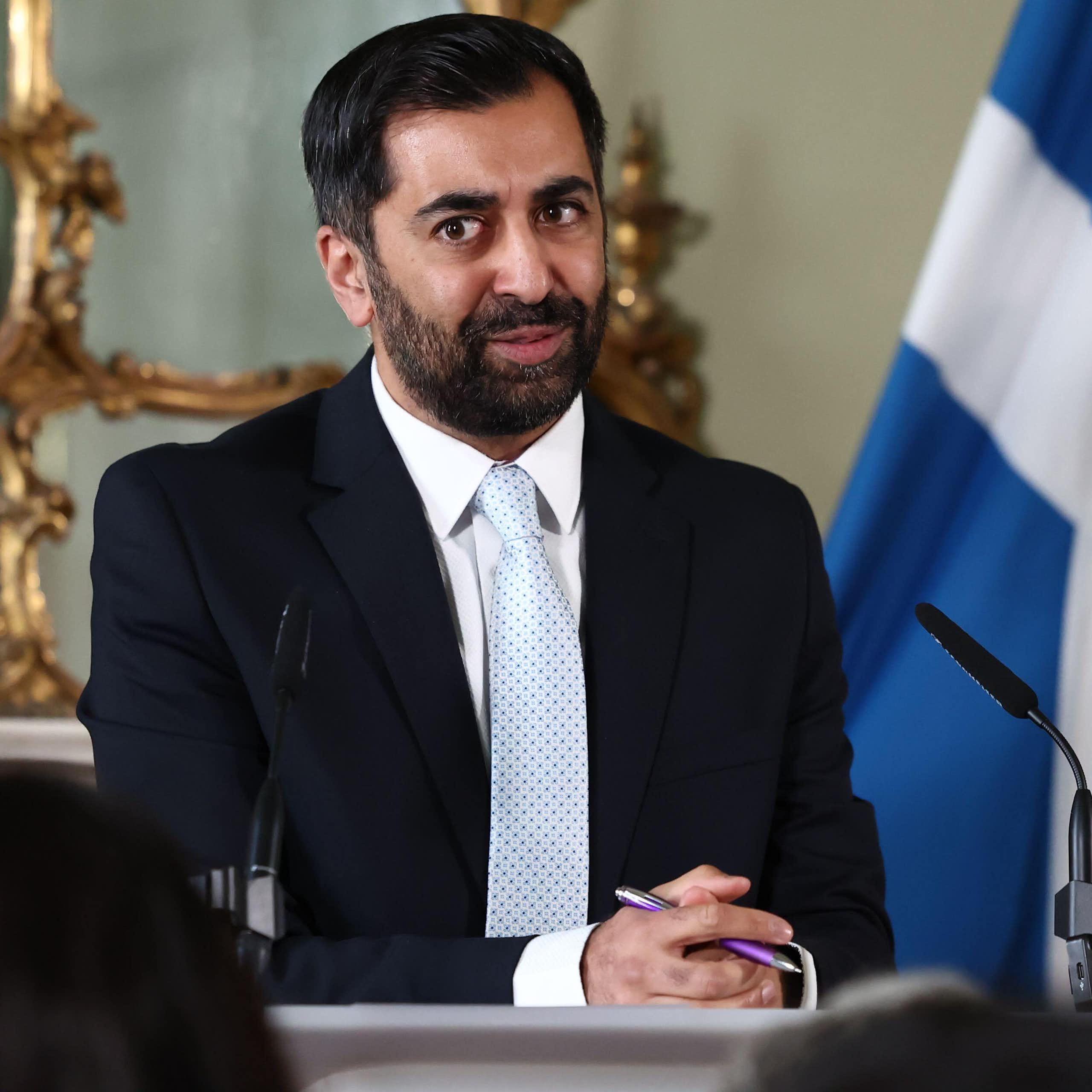 Humza Yousaf giving a speech in front of a Scottish flag. 
