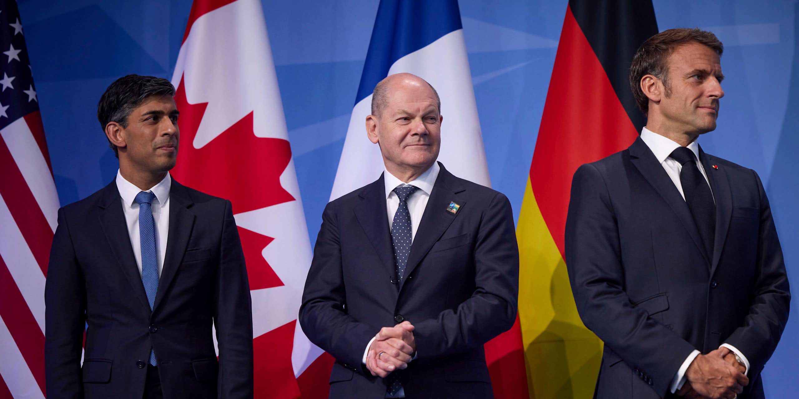 Rishi Sunak, Olaf Scholz, and Emmanuel Macron in front of flags.